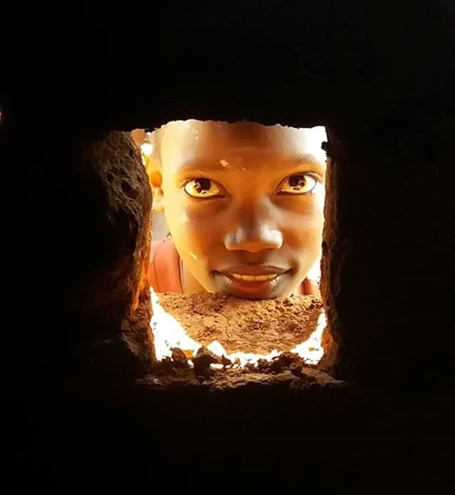 Child looking at camera through hole in wall